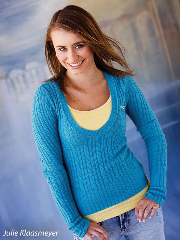 Studio portrait of smiling teen in blue and yellow top posed against romantic European-style backdrop, great for school and dance sessions.