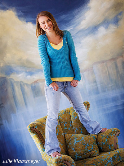 Energetic portrait with teen standing on chair in front of painted Venice waterway, ideal for expressive senior photography.