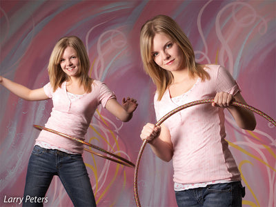 Side-by-side portrait of girl with hula hoop in front of colorful ribbon-inspired pink backdrop, designed for lively school or senior sessions.